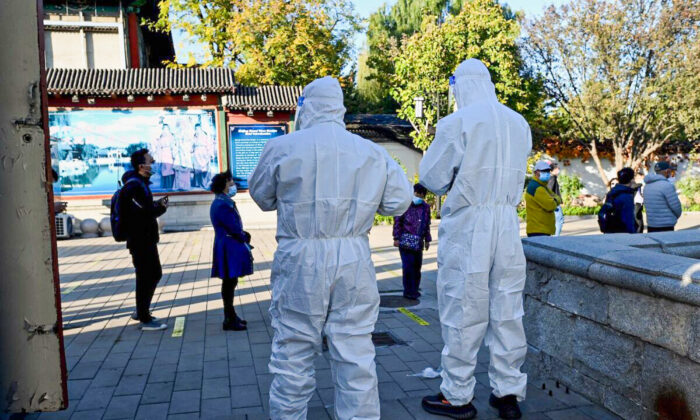 A health workers look at people queueing for swab tests for COVID-19 at a nucleic acid collection station in Beijing on Oct. 26, 2021. (Noel Celis/AFP via Getty Images)