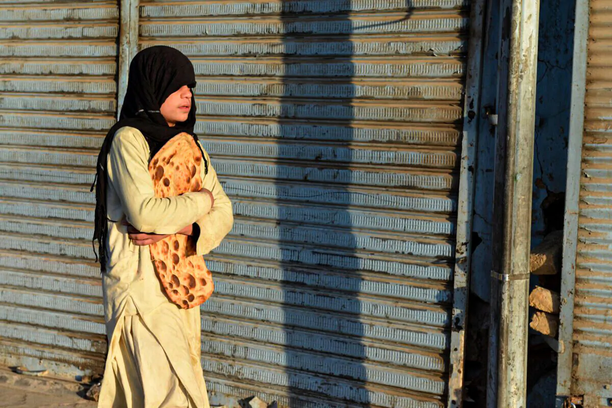 A boy carries freshly baked bread along a street in Kandahar on October 27, 2021. 24 million people in Afghanistan are in need of humanitarian assistance after August 15. (Javed Tanveer/ AFP)