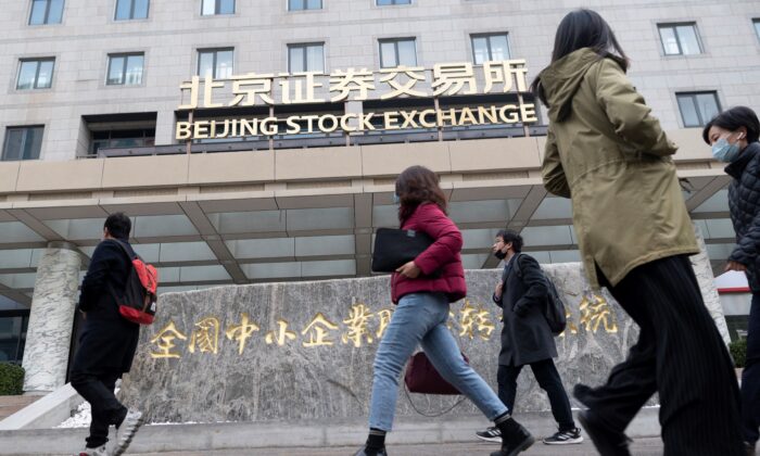 People walk past the Beijing Stock Exchange on its first day of trading in Beijing, on Nov. 15, 2021. (Wang Zhao/AFP via Getty Images)