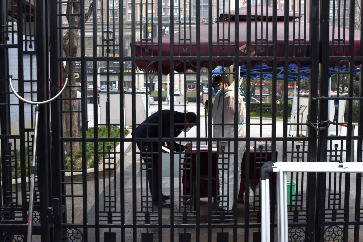 A security guard checks the information of a man at the entrance of a residential area that is under restriction following a recent COVID-19 outbreak in Xian, in China's northern Shaanxi Province on December 23, 2021. (STR/AFP via Getty Images)