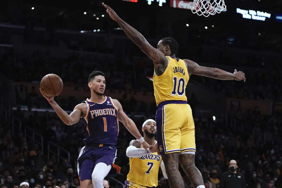 Phoenix Suns' Devin Booker, left, passes the ball under pressure by Los Angeles Lakers' DeAndre Jordan during first half of an NBA basketball game in Los Angeles on Dec. 21, 2021. (AP Photo/Jae C. Hong)