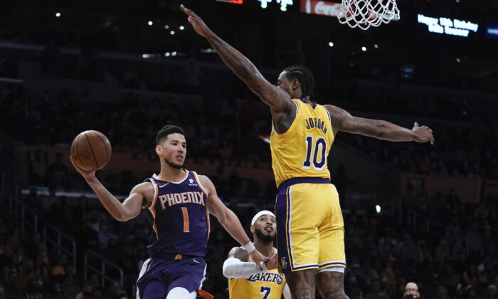 Phoenix Suns' Devin Booker, left, passes the ball under pressure by Los Angeles Lakers' DeAndre Jordan during first half of an NBA basketball game in Los Angeles on Dec. 21, 2021. (AP Photo/Jae C. Hong)