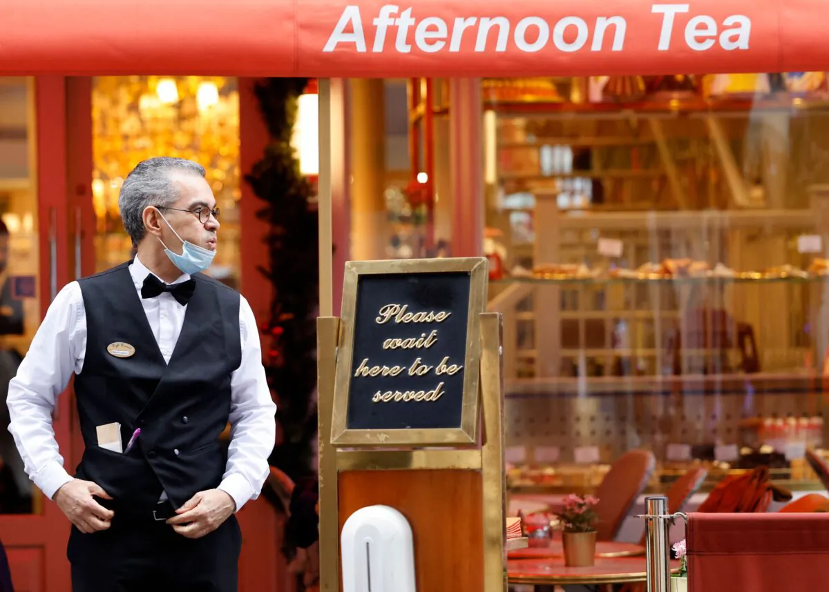 A hospitality industry worker waits for customers outside a restaurant in London on Dec. 21, 2021. (Tolga Akmen/AFP via Getty Images)