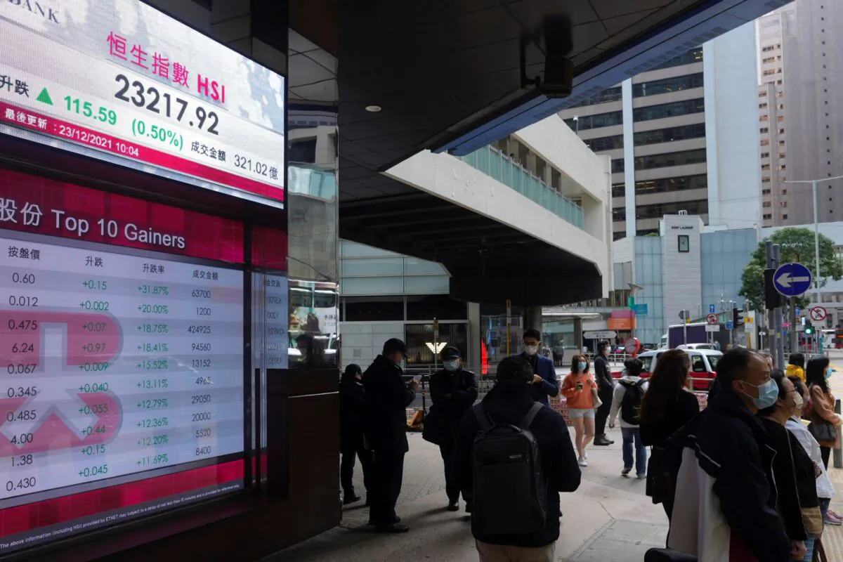 People walk past a bank's electronic board showing the Hong Kong share index at Hong Kong Stock Exchange, in Hong Kong, China, on Dec. 23, 2021. (Vincent Yu/AP Photo)