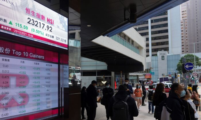People walk past a bank's electronic board showing the Hong Kong share index at Hong Kong Stock Exchange, on Dec. 23, 2021. (Vincent Yu/AP Photo)
