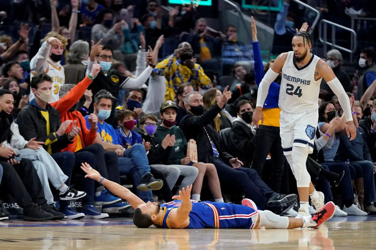 Golden State Warriors guard Stephen Curry, bottom, celebrates after shooting a 3-point basket next to Memphis Grizzlies forward Dillon Brooks (24) during the second half of an NBA basketball game in San Francisco, on Dec. 23, 2021. (Jeff Chiu/AP Photo)