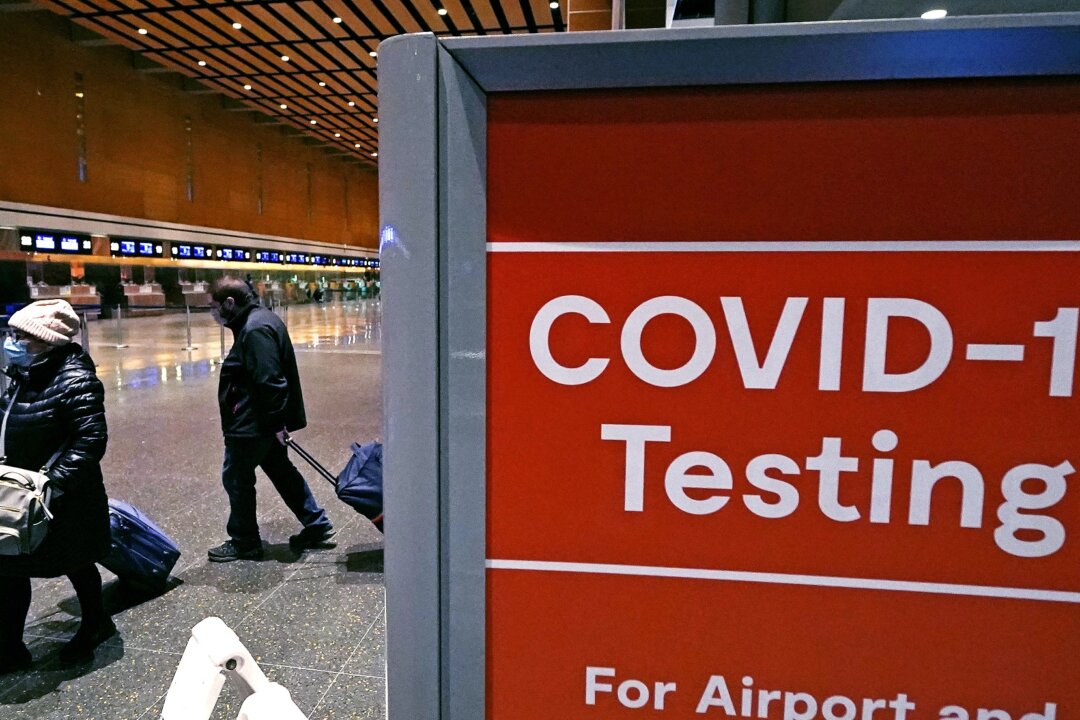 Travelers pass a sign near a COVID-19 testing site in Terminal E at Logan Airport in Boston, on Dec. 21, 2021. (Charles Krupa/AP Photo)