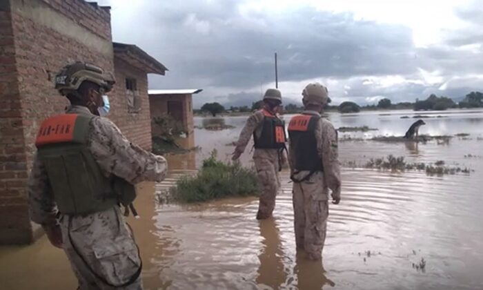 A video photo showing soldiers walking next to flood waters, after the flooding in Bolivia. (AP/Screenshot via The Epoch Times)