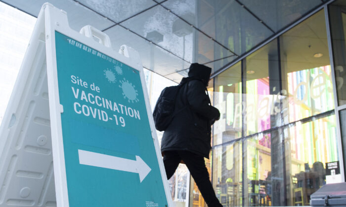 A man walks by a COVID-19 vaccination sign in Montreal on Dec. 23, 2021. (Graham Hughes/The Canadian Press)