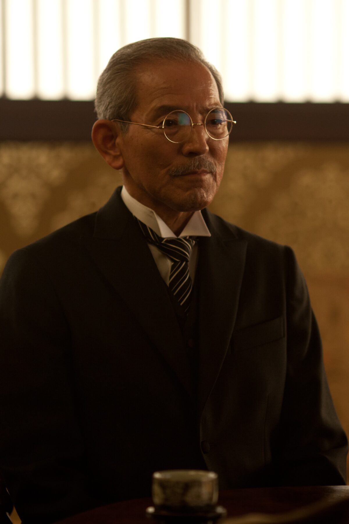 man with dark suit and glasses in EMPEROR
