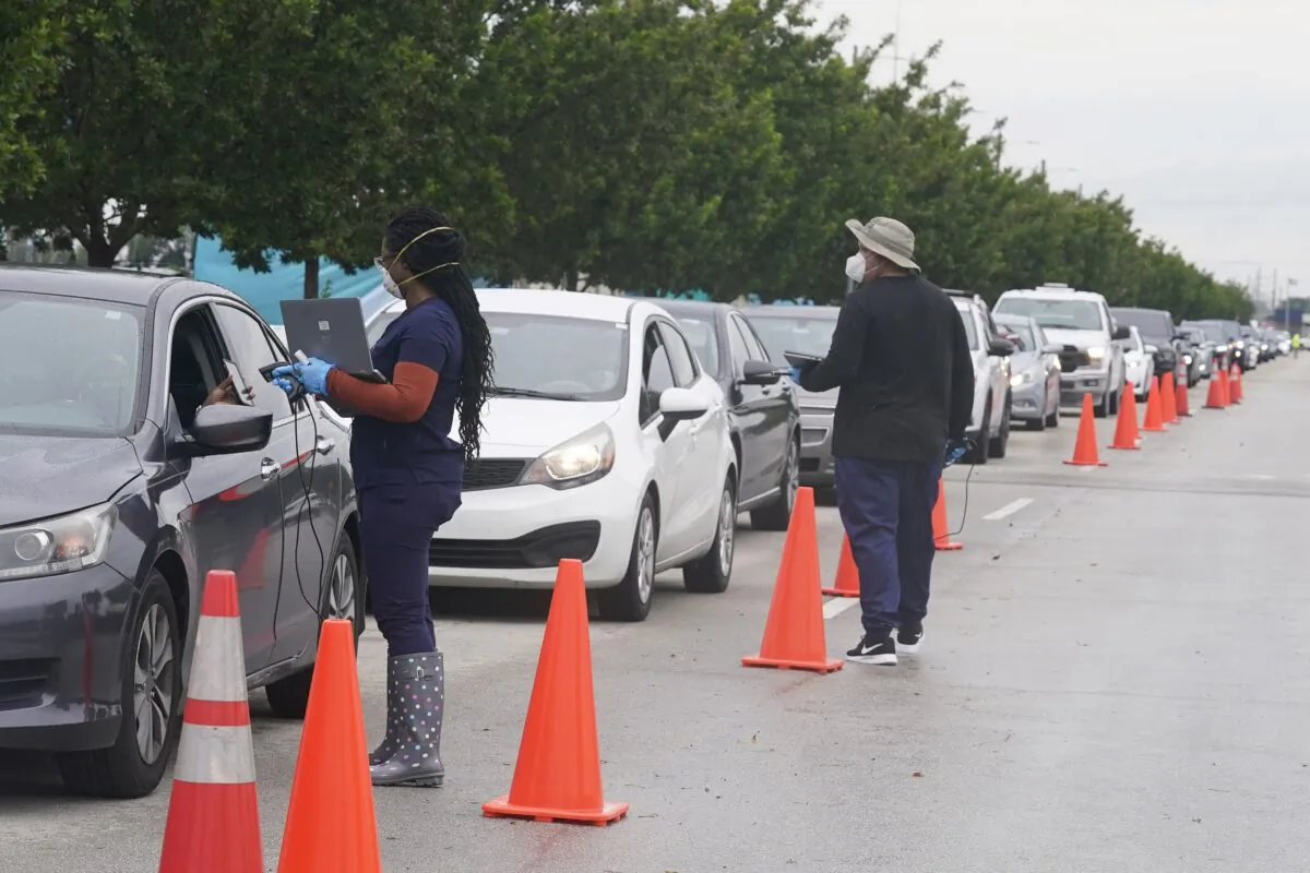 Employees of Nomi Health check in a long line of people for COVID-19 tests in North Miami on Dec. 21, 2021. (Marta Lavandier/AP Photo)