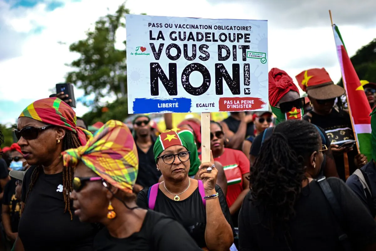 A demonstrator holds a sign opposing the COVID-19 vaccination during a protest march over coronavirus measures and social grievances in Pointe-a-Pitre in the French Caribbean island of Guadeloupe, on Nov. 27, 2021. (Christophe Archambault/AFP via Getty Images)