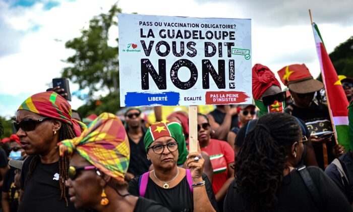 A demonstrator holds a sign opposing the COVID-19 vaccination during a protest march over coronavirus measures and social grievances in Pointe-a-Pitre in the French Caribbean island of Guadeloupe, on Nov. 27, 2021. (Christophe Archambault/AFP via Getty Images)