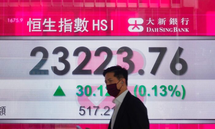 A man walks past a bank's electronic board showing the Hong Kong share index at Hong Kong Stock Exchange, on Dec. 24, 2021. (Vincent Yu/AP Photo)