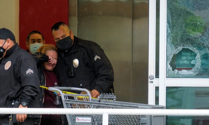 A police officer comforts a woman at the scene where two people were struck by gunfire in a shooting at a Burlington store as part of a chain formerly known as Burlington Coat Factory in North Hollywood, Calif., on Dec. 23, 2021. (Ringo H.W. Chiu/AP Photo)