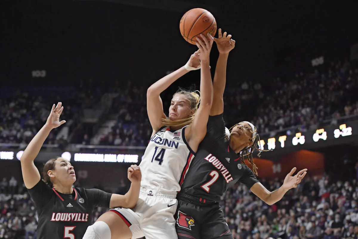 Connecticut's Dorka Juhasz (14) reaches up for a rebound against Louisville's Ahlana Smith (2) as Louisville's Mykasa Robinson (5) defends, during an NCAA college basketball game in Uncasville, Conn., on Dec. 19, 2021. (Jessica Hill/AP Photo)