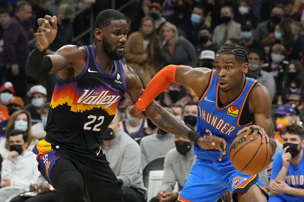Oklahoma City Thunder guard Shai Gilgeous-Alexander drives past Phoenix Suns center Deandre Ayton (22), during an NBA game in Phoenix, Ariz., on Dec. 23, 2021. (Rick Scuteri/AP Photo)