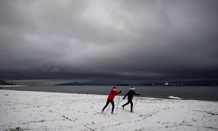 People cross-country ski at Locarno Beach after an overnight snowfall in Vancouver on Dec. 25, 2021. (The Canadian Press/Darryl Dyck)
