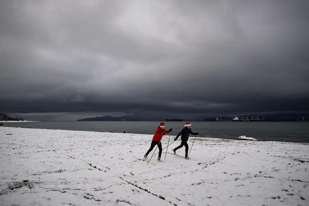 People cross-country ski at Locarno Beach after an overnight snowfall in Vancouver on Dec. 25, 2021. (The Canadian Press/Darryl Dyck)