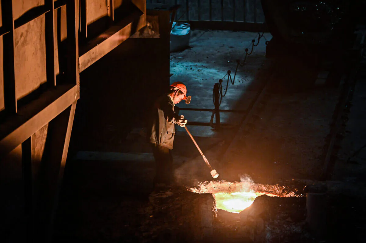 A worker extracts a sample of molten metal during a government organised tour at a Tiangong International plant, makers of high quality steel and tools, in  China's eastern Jiangsu Province on Oct. 12, 2020. (Hector Retamal/AFP via Getty Images)