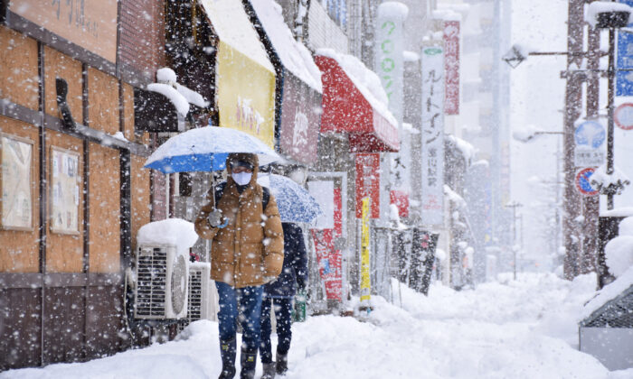 People walk along a street in heavy snow in Toyama, Japan, brought by an extreme cold front along western and northern parts of the country on Dec. 27, 2021. (JIJI Press/AFP via Getty Images)