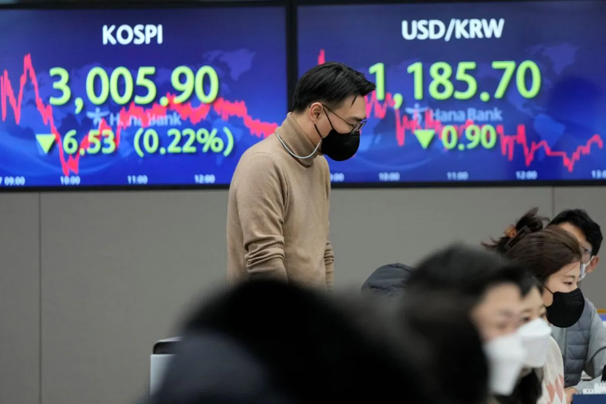 A currency trader passes by screens showing the Korea Composite Stock Price Index (KOSPI) (L) and the foreign exchange rate between U.S. dollar and South Korean won, at the foreign exchange dealing room of the KEB Hana Bank headquarters in Seoul, South Korea, on Dec. 27, 2021. (Ahn Young-joon/AP Photo)