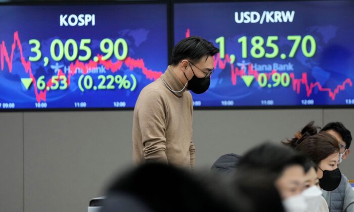 A currency trader passes by screens showing the Korea Composite Stock Price Index (KOSPI) (L) and the foreign exchange rate between U.S. dollar and South Korean won, at the foreign exchange dealing room of the KEB Hana Bank headquarters in Seoul, South Korea, on Dec. 27, 2021. (Ahn Young-joon/AP Photo)