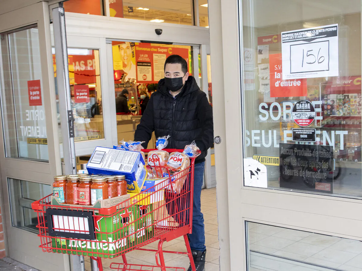 A man walks by a sign indicating reduced capacity at a grocery store in Montreal on Dec. 20, 2021, as measures reducing capacity for stores, bars, restaurants, and gyms come into effect in Quebec. (The Canadian Press/Graham Hughes)