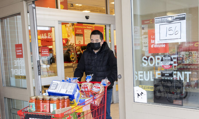 A man walks by a sign indicating reduced capacity at a grocery store in Montreal on Dec. 20, 2021, as measures reducing capacity for stores, bars, restaurants, and gyms come into effect in Quebec. (The Canadian Press/Graham Hughes)