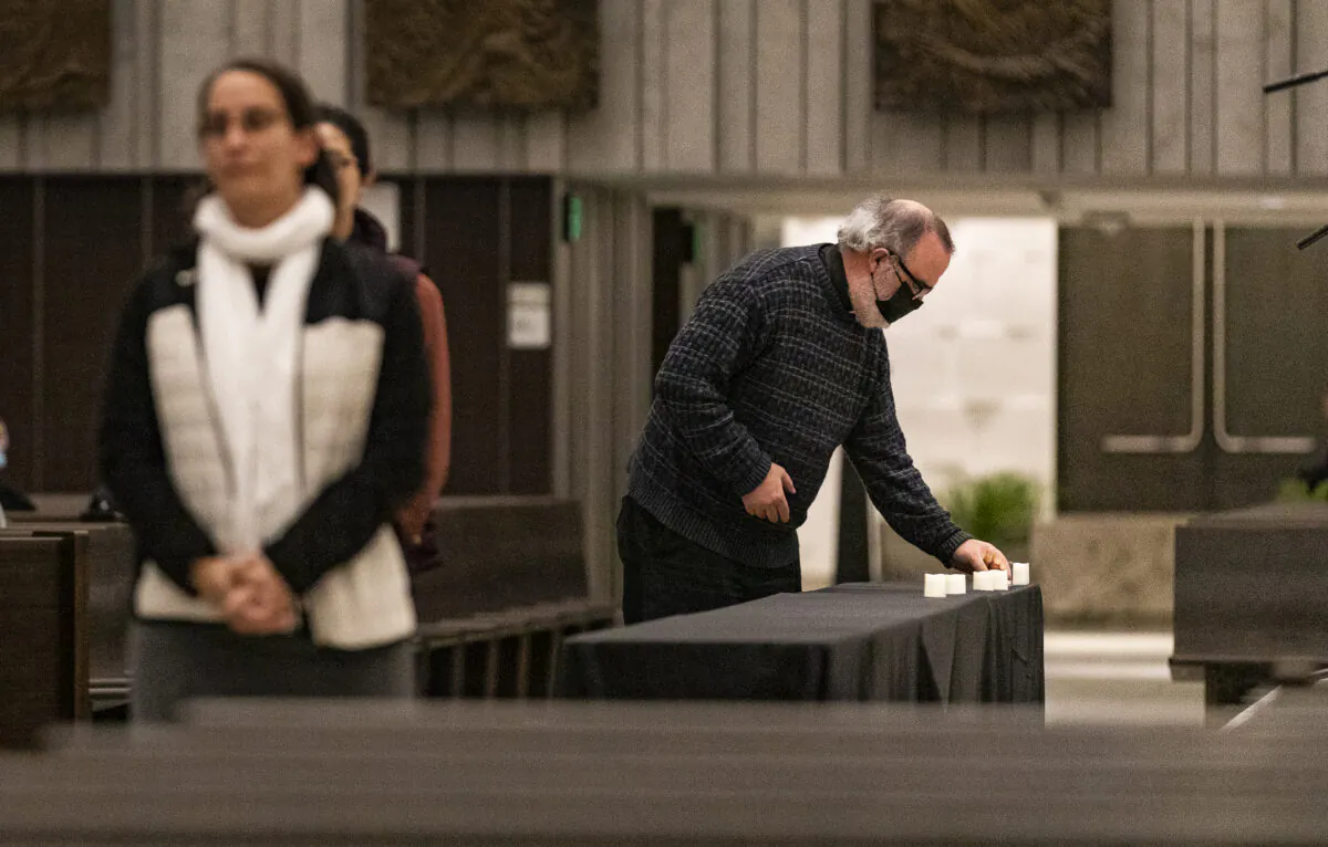 Churchgoers place candles on a table in memory homeless persons who have passed at a inter-religious prayer memorial service at Christ Cathedral in Garden Grove, Calif., on Dec. 21, 2021. (John Fredricks/The Epoch Times)