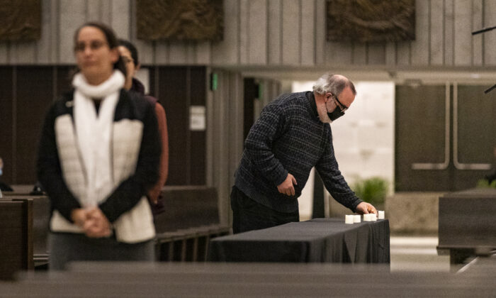 Churchgoers place candles on a table in memory homeless persons who have passed at a inter-religious prayer memorial service at Christ Cathedral in Garden Grove, Calif., on Dec. 21, 2021.