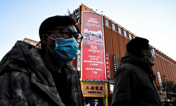 People walk past a billboard promoting the annual "Singles Day" on Nov. 11, the biggest shopping day of the year, at a shopping mall complex in Beijing on Nov. 10, 2021. (Jade Gao/AFP via Getty Images)