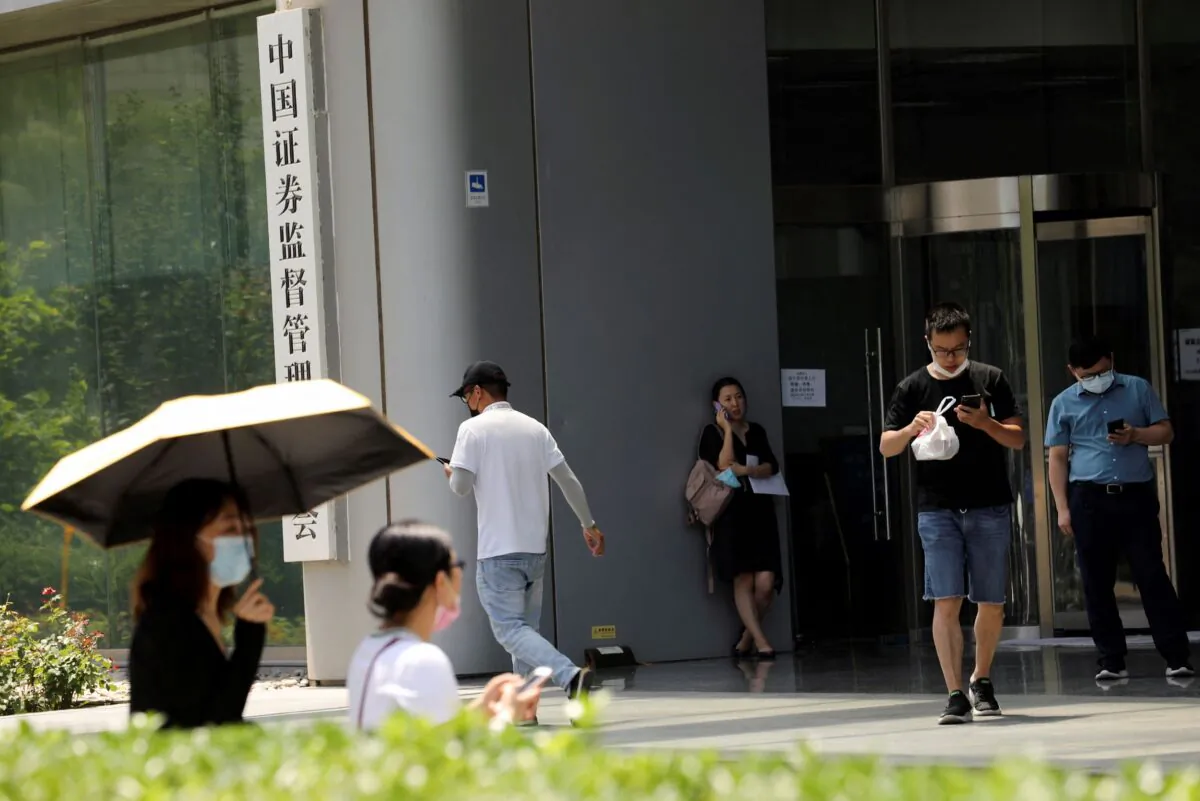 People walk past the China Securities Regulatory Commission (CSRC) sign at its building on the Financial Street in Beijing, on July 9, 2021. (Tingshu Wang/Reuters)