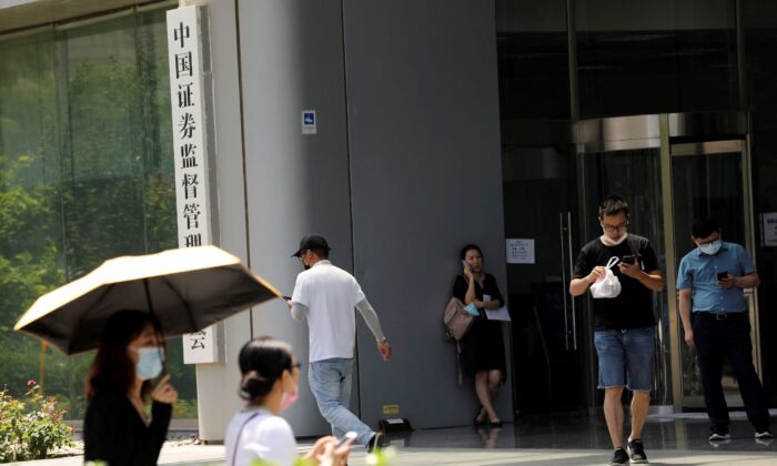 People walk past the China Securities Regulatory Commission (CSRC) sign at its building on the Financial Street in Beijing, on July 9, 2021. (Tingshu Wang/Reuters)