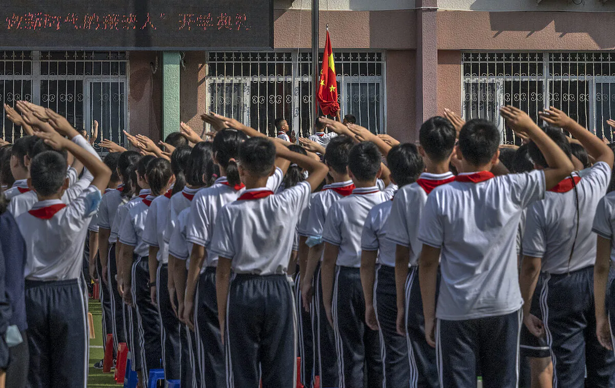 Students salute as a national flag is raised during a ceremony on the first day of the new school year at an elementary school in Beijing, China, on Sept. 1, 2021. (Kevin Frayer/Getty Images)