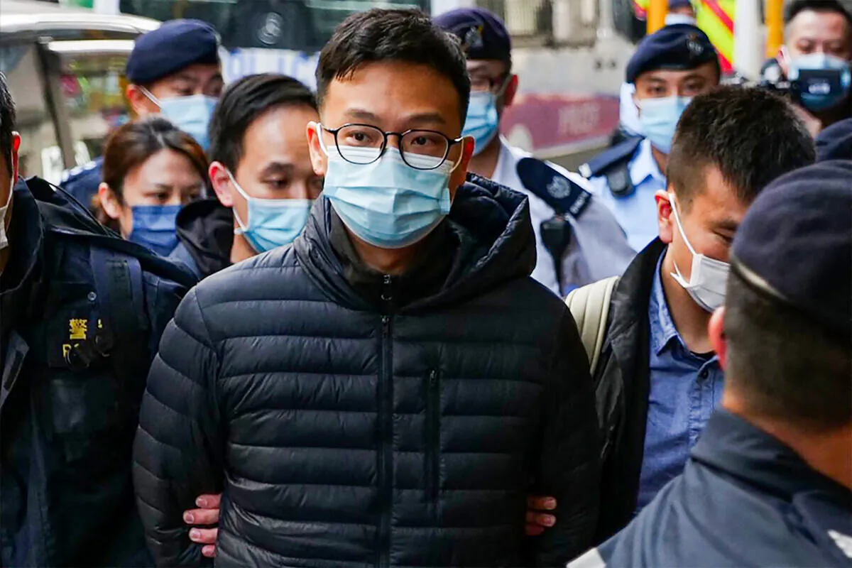 Stand News chief editor Patrick Lam is brought to the news outlet's office building in handcuffs after police were deployed to search the premises in Hong Kong's Kwun Tong district on Dec 29, 2021. (Daniel Suen/AFP via Getty Images)