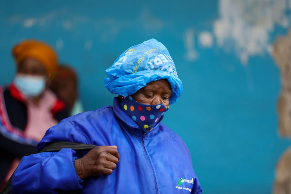 A woman wearing a protective face mask against COVID-19 and a plastic bag on her head to protect from the rain looks on at Tsomo, a town in the Eastern Cape province of South Africa, on Dec. 2, 2021. (Siphiwe Sibeko/Reuters)
