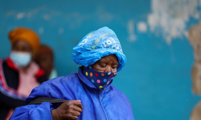A woman wearing a protective face mask against COVID-19 and a plastic bag on her head to protect from the rain looks on at Tsomo, a town in the Eastern Cape province of South Africa, on Dec. 2, 2021. (Siphiwe Sibeko/Reuters)