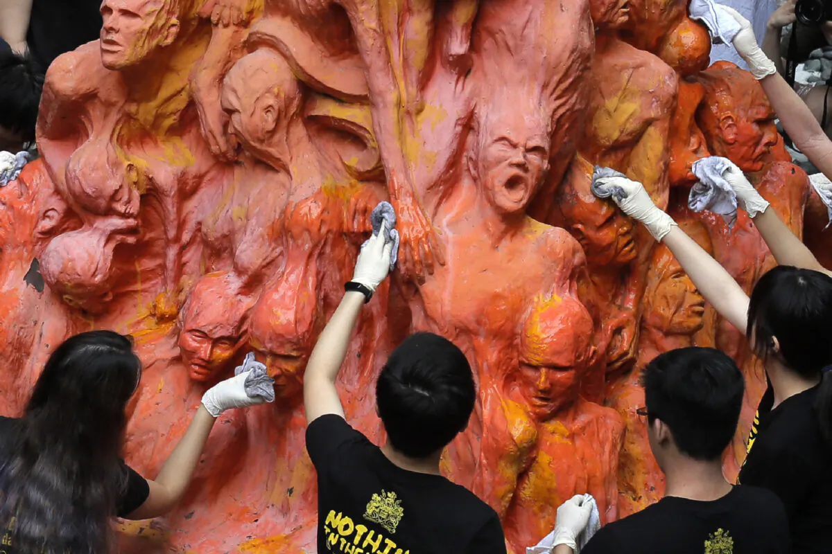 University students clean the "Pillar of Shame" statue, a memorial for those killed in the 1989 Tiananmen crackdown, at the University of Hong Kong, on June 4, 2019. (Kin Cheung/AP Photo)