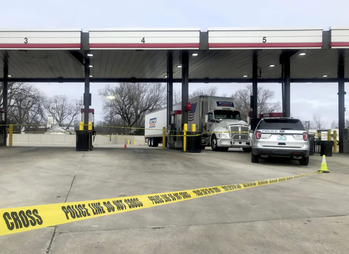 A tractor trailer is stopped behind police tape as law enforcement investigate the scene of a carjacking and shooting at a QuikTrip in St. Peters, Mo., on Dec. 29, 2021. (Hillary Levin/St. Louis Post-Dispatch via AP)