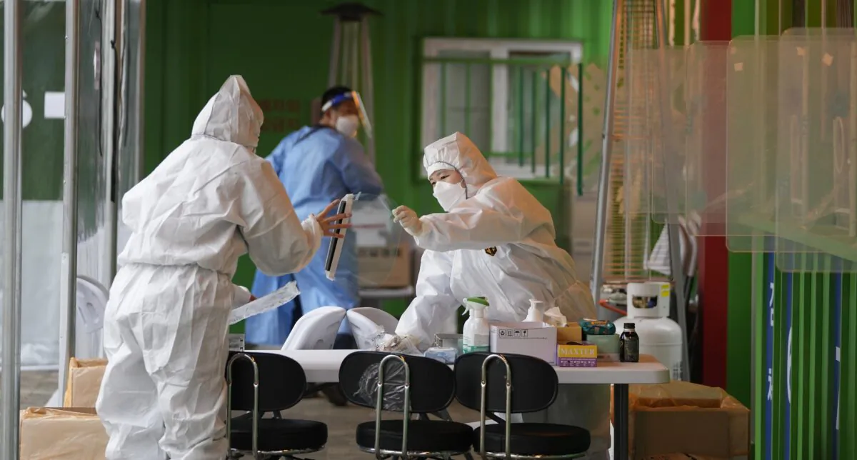 Medical workers wearing protective gear prepare to take samples at a temporary screening clinic for the coronavirus in Seoul, South Korea, on Dec. 29, 2021. (Lee Jin-man/AP Photo)