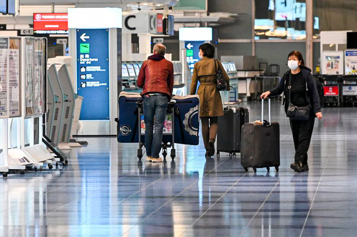 Travelers walking past check-in counters at an international flight departure floor at Tokyo's Haneda airport, on Dec. 1, 2021. (Kazuhiro Nogi/AFP via Getty Images)
