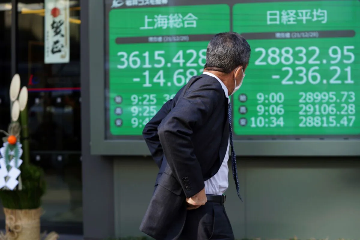 A man wearing a protective mask looks at an electronic stock board showing Japan's Nikkei 225 and Shanghai indexes at a securities firm with a traditional New Year decoration at its entrance in Tokyo, Japan, on Dec. 29, 2021. (Eugene Hoshiko/AP Photo)