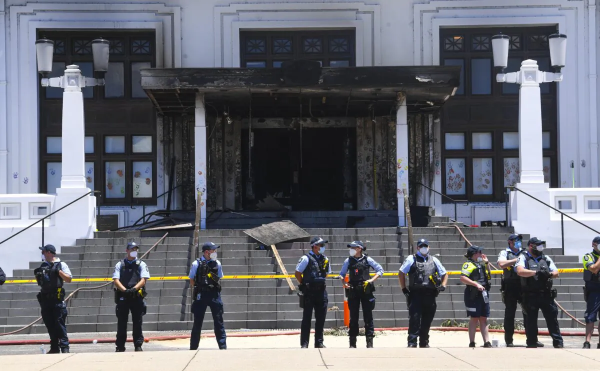 Police officers stand guard outside the fire damaged entrance to Old Parliament House in Canberra, Australia, on Dec. 30, 2021. (AAP Image/Lukas Coch)