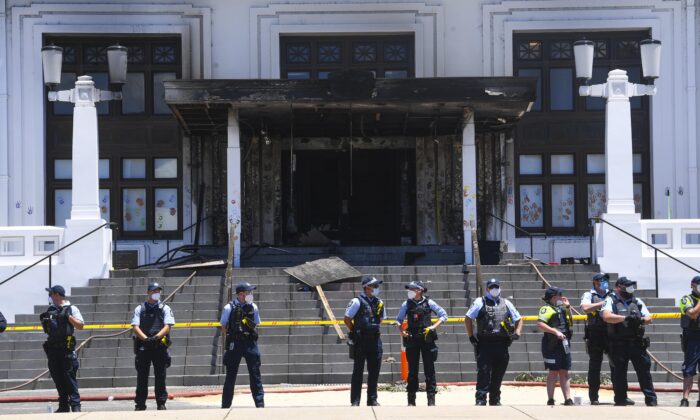 Police officers stand guard outside the fire damaged entrance to Old Parliament House in Canberra, Australia, on Dec. 30, 2021. (AAP Image/Lukas Coch) 