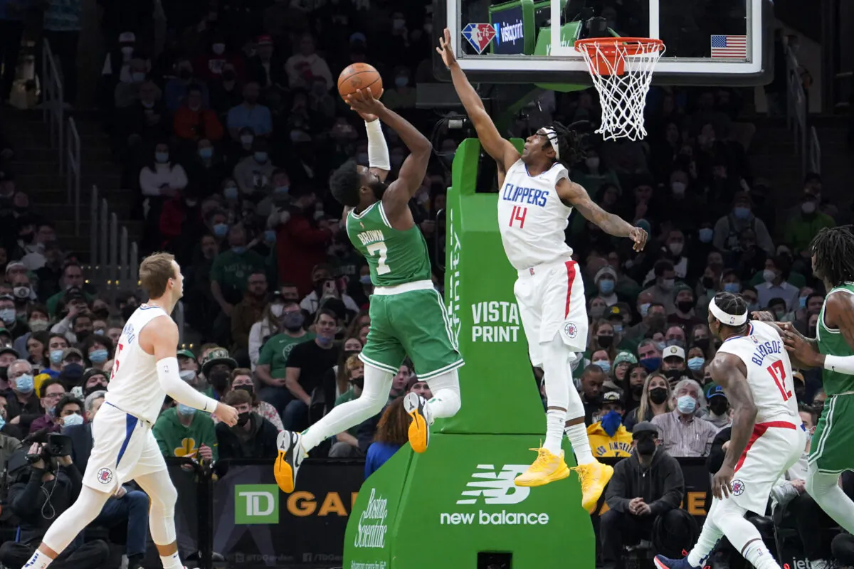 Boston Celtics guard Jaylen Brown (7) shoots over Los Angeles Clippers guard Terance Mann (14) during the first half of an NBA basketball game in Boston on Dec. 29, 2021. (AP Photo/Mary Schwalm)