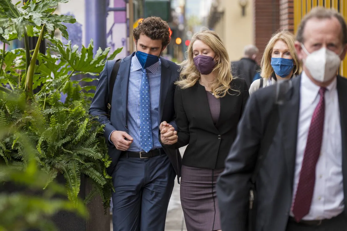 Former Theranos CEO Elizabeth Holmes, second left, with her partner, Billy Evans, left, and mother, Noel Holmes, back right, leaves federal court in San Jose, Calif., on Dec. 23, 2021. (Nic Coury/AP Photo)