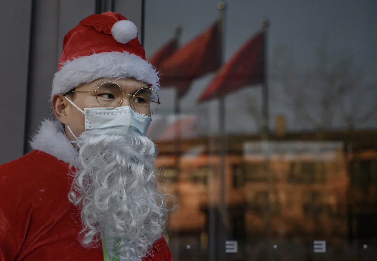 A Chinese worker dressed in a Santa Claus suit welcomes customers as part of a Christmas event at a shopping mall in Beijing, on Dec. 24, 2020. (Kevin Frayer, Getty Images)