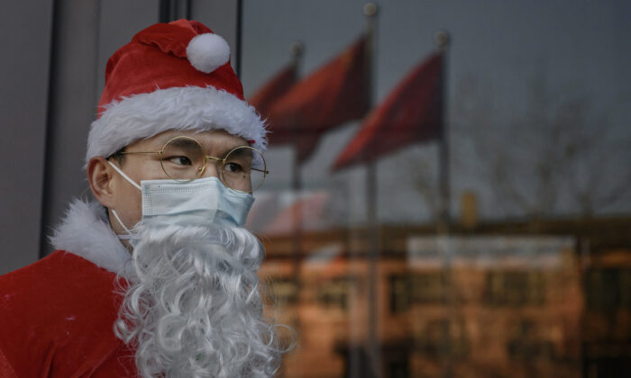 A Chinese worker dressed in a Santa Claus suit welcomes customers as part of a Christmas event at a shopping mall in Beijing, on Dec. 24, 2020. (Kevin Frayer, Getty Images)