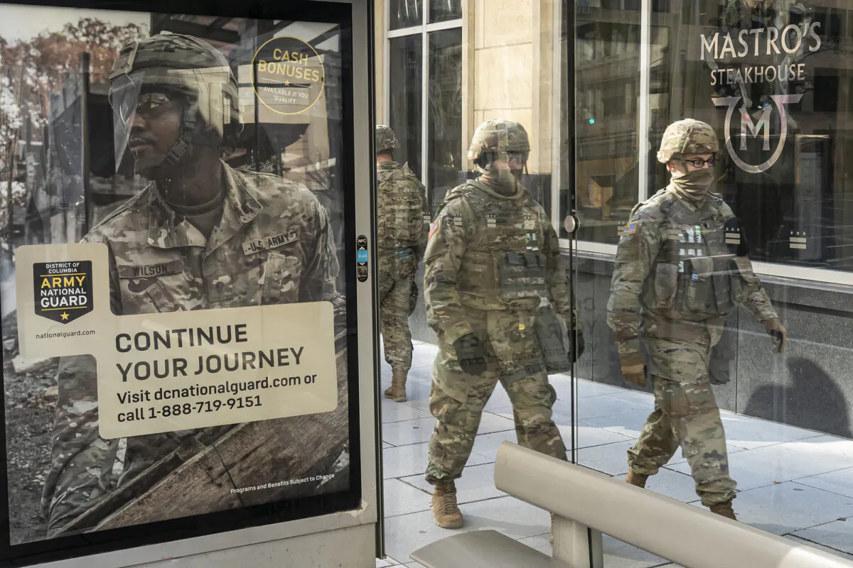 National Guard troops walk past a recruitment sign for the Army National Guard in Washington, on Jan. 19, 2021. (Nathan Howard/Getty Images)